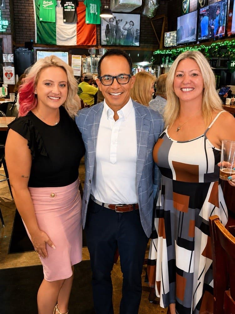 Three Impact members smiling together at an evening mixer